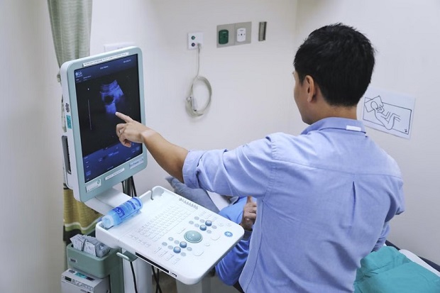  ​Dr Tan Yu Guang using an ultrasound scan to show patient Tony Wong (not his real name) that the cancer in his bladder is gone.PHOTO LIANHE ZAOBAO 