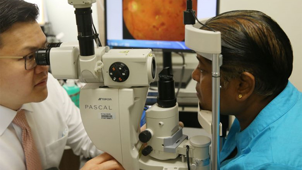  ​Dr Gavin Tan, a consultant ophthalmologist with SNEC's surgical retina department, demonstrating how laser treatment can be used for a patient's diabetic eye disease.   ST PHOTO SEAH KWANG PENG
