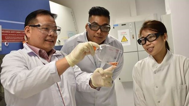  ​Three members of the NUS research team holding their new test kit that prevents the hand, foot and mouth disease from spreading by detecting it early  (From left) Associate Professor Justin Chu and research assistants Nyo Min and Regina Lee. 