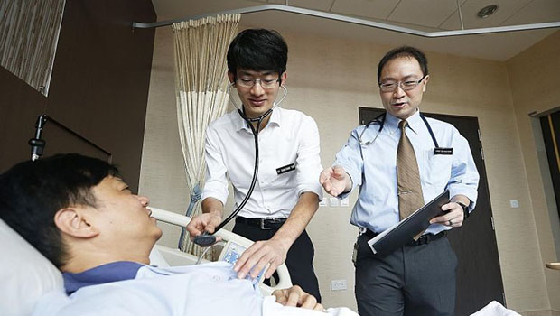  ​​Dr Jonathan Yap (left), associate consultant in the National Heart Centre Singapore's cardiology department, seeing a patient with his mentor, Associate Professor Yeo Khung Keong, a senior consultant. The mentorship programme is among hospital schemes that aim to help young doctors cope with stress.  ST PHOTO TIMOTHY DAVID